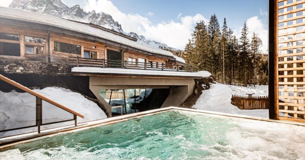 Beheizter Außenpool des Caravanpark Sexten im Winter mit verschneiten Dolomiten und alpinem Wellnessbereich in Südtirol.